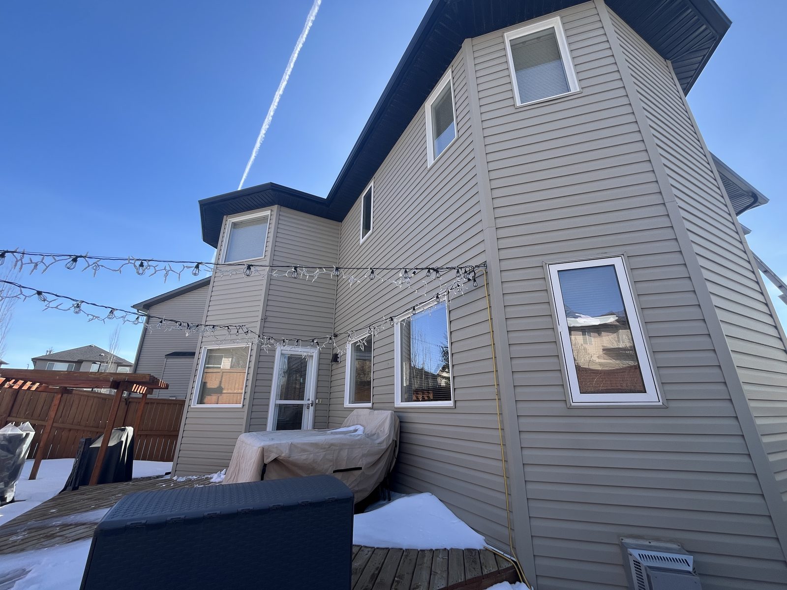 Rear elevation of a home with clean windows beneath patio string lights